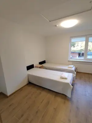 two beds in a room with wooden floors and a window at Radikiai House in Smiltynai