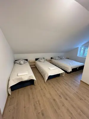 a room with two beds and a wooden floor at Radikiai House in Smiltynai