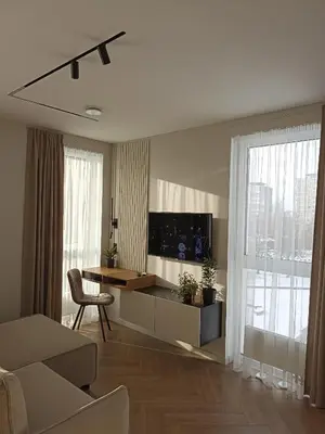 a living room with a television and a table and chairs at Apartments with a balcony and an impressive terrace on the roof of the house in Vilnius