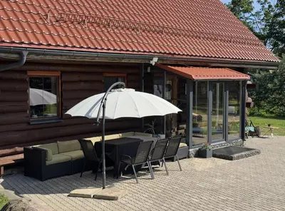a table and chairs with an umbrella in front of a building at Kaimo sodyba Dešimt Beržų in Gudžioniai