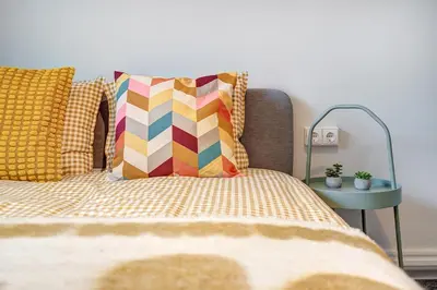 a bed with a colorful pillow and a side table at Funky Penthouse City Center in Kaunas