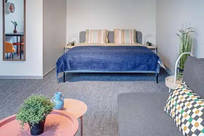 a bedroom with a bed with a blue blanket and a table at Funky Penthouse City Center in Kaunas