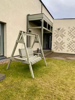 a chair sitting on the grass in front of a building at Apartamentai Ornamentai in Druskininkai
