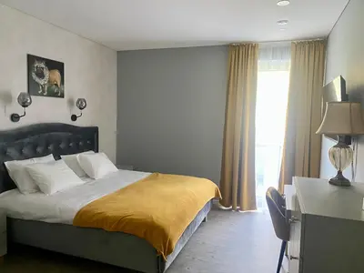 a bedroom with a large bed and a window at Apartamentai Ornamentai in Druskininkai