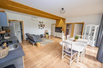 a kitchen and living room with a white table and chairs at Poilsio oazė in Vynupė