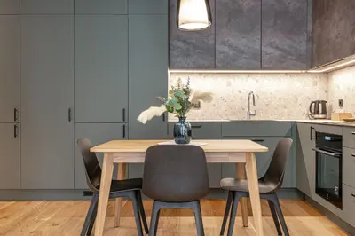 a kitchen with a wooden table with chairs and a vase of flowers at Brand New White Lotus Apartment 3 by Reside Baltic in Vilnius