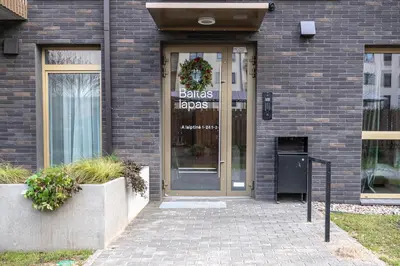 a glass door of a building with a sign on it at Brand New White Lotus Apartment 3 by Reside Baltic in Vilnius