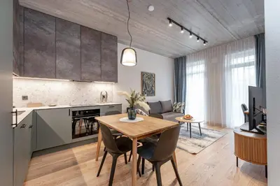 a kitchen and a living room with a table and chairs at Brand New White Lotus Apartment 3 by Reside Baltic in Vilnius