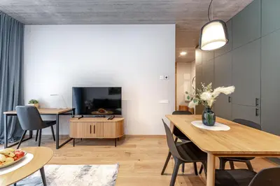a living room with a dining table and a tv at Brand New White Lotus Apartment 3 by Reside Baltic in Vilnius