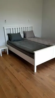 a large white bed in a room with a wooden floor at IG House in Druskininkai