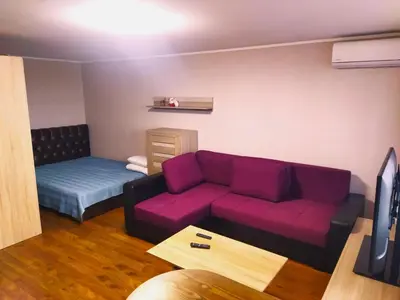 a living room with a purple couch and a bed at ITAJA apartment 66 in Šiauliai