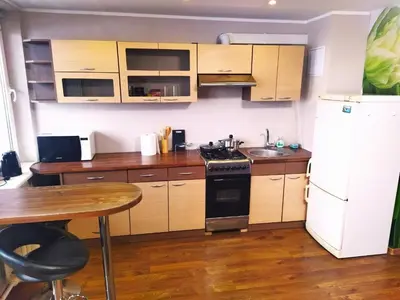 a kitchen with wooden cabinets and a white refrigerator at ITAJA apartment 66 in Šiauliai