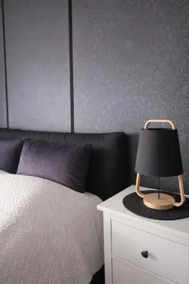 a bed with a black lamp on a night stand at Downtown Boulevard View Residence in Šiauliai