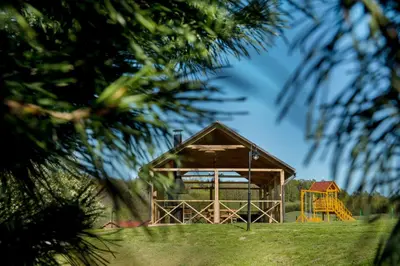 a wooden pavilion with a playground in a park at Sodyba ant ežero kranto pas Radvilą in Kiemeliai