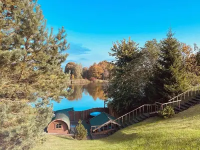 a cabin next to a lake with a wooden fence at Sodyba ant ežero kranto pas Radvilą in Kiemeliai