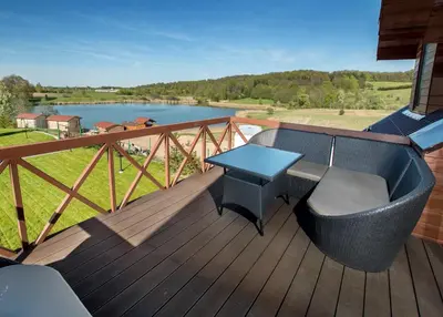 a table and chairs on a deck with a view of a lake at Sodyba ant ežero kranto pas Radvilą in Kiemeliai