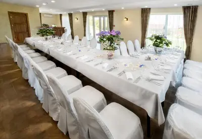 a row of long tables with white chairs and flowers at Sodyba ant ežero kranto pas Radvilą in Kiemeliai