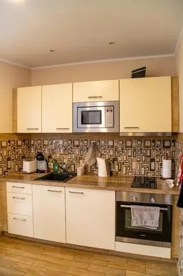 a kitchen with white cabinets and a microwave at NK apartments in Druskininkai