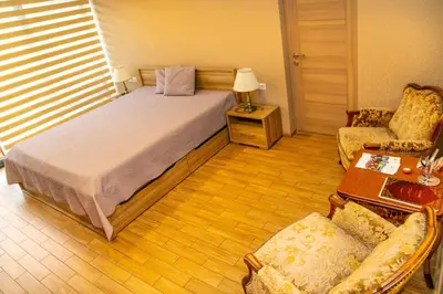 a bedroom with a bed and a chair and a table at NK apartments in Druskininkai