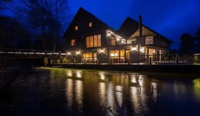 a large house with lights on the water at night at Sodyba Ignė in Druskininkai
