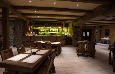 a restaurant with wooden tables and chairs and a bar at Sodyba Ignė in Druskininkai