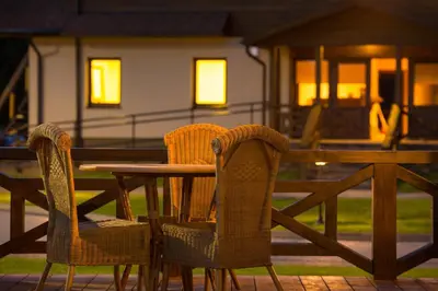 a wooden table and chairs with a table and a house at Sodyba Ignė in Druskininkai