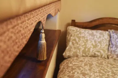 a wooden bed with a tassel next to a pillow at Karčema Ružava in Molainiai