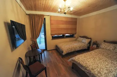 a bedroom with two beds and a table and a chair at Karčema Ružava in Molainiai