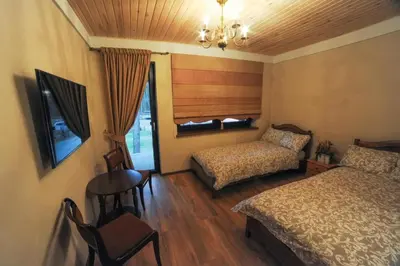 a bedroom with two beds and a table and a chair at Karčema Ružava in Molainiai