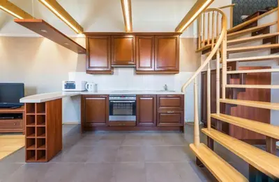 a kitchen with wooden cabinets and a spiral staircase at Central apartments 3 x Free parking x SELF CHECK-IN in Vilnius