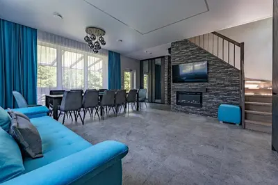 a living room with a blue couch and a dining room at Zalesossodyba in Purnuškis