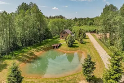 an overhead view of a pond with a house in the background at Zalesossodyba in Purnuškis
