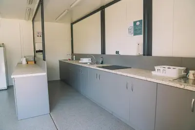 a kitchen with white cabinets and a sink and mirrors at Natur Camp Birštonas Small Cabins in Birštonas