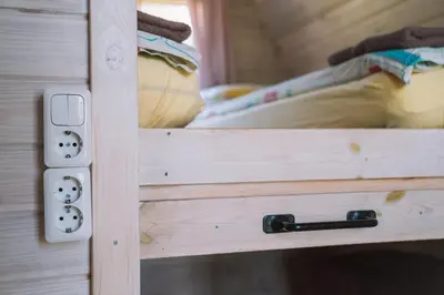 a wooden cabinet with a door open with a bed at Natur Camp Birštonas Small Cabins in Birštonas