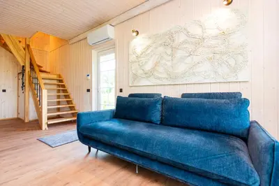a blue couch in a living room with a staircase at Namelis ant ežero kranto 