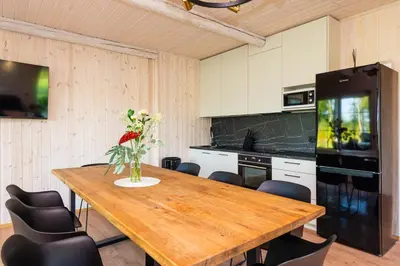 a kitchen with a wooden table and black appliances at Namelis ant ežero kranto 