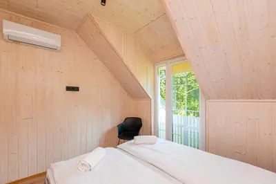 a room with a bed with a chair and a window at Namelis ant ežero kranto 