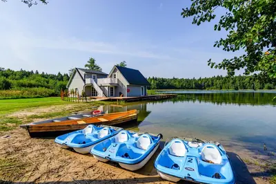 three boats on the shore of a lake with a house at Namelis ant ežero kranto 