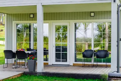 a screened porch with black chairs and a table at Namelis ant ežero kranto 