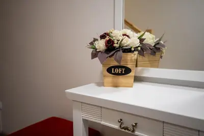 a bouquet of flowers sitting on a table in front of a mirror at Loft apartment in Druskininkai