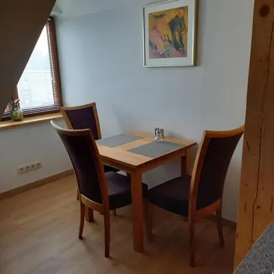 a dining room table and four chairs in a room at S Neries 19 apartamentai su parkingu in Šiauliai