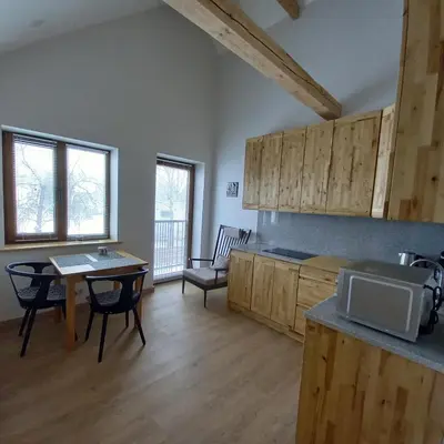a kitchen with wooden cabinets and a table and a dining room at S Neries 19 apartamentai su parkingu in Šiauliai