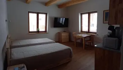 a bedroom with two beds and a television and a table at S Neries 19 apartamentai su parkingu in Šiauliai