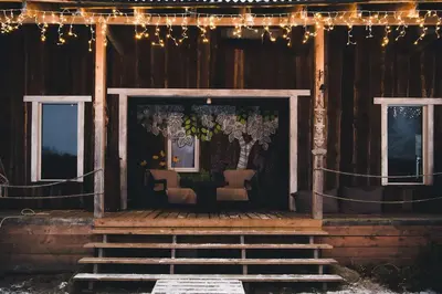 a porch of a wooden house with chairs and lights at Daugirdėnų sodyba in Didžiuliai