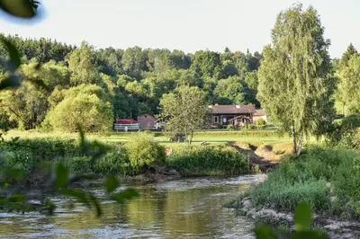 a house on the side of a river at Daugirdėnų sodyba in Didžiuliai