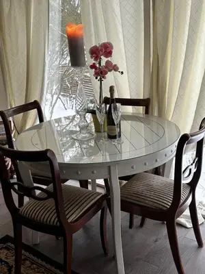 a glass table with two chairs and a table with flowers on it at Cosy apartment in Kaunas