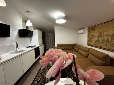 a living room with a couch and a table with pink flowers at Cosy apartment in Kaunas