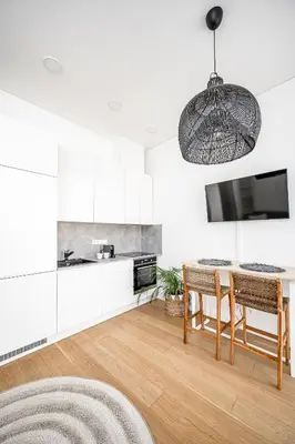 a kitchen with white cabinets and a table with chairs at Bali style apartment with balcony near Gates of Dawn in Vilnius