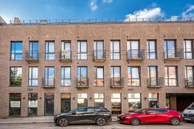 two cars parked in front of a brick building at Bali style apartment with balcony near Gates of Dawn in Vilnius