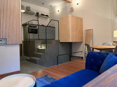 a living room with a blue couch and a kitchen at CLASSY PLACE IN VILNIUS CENTER FOR TWO in Vilnius